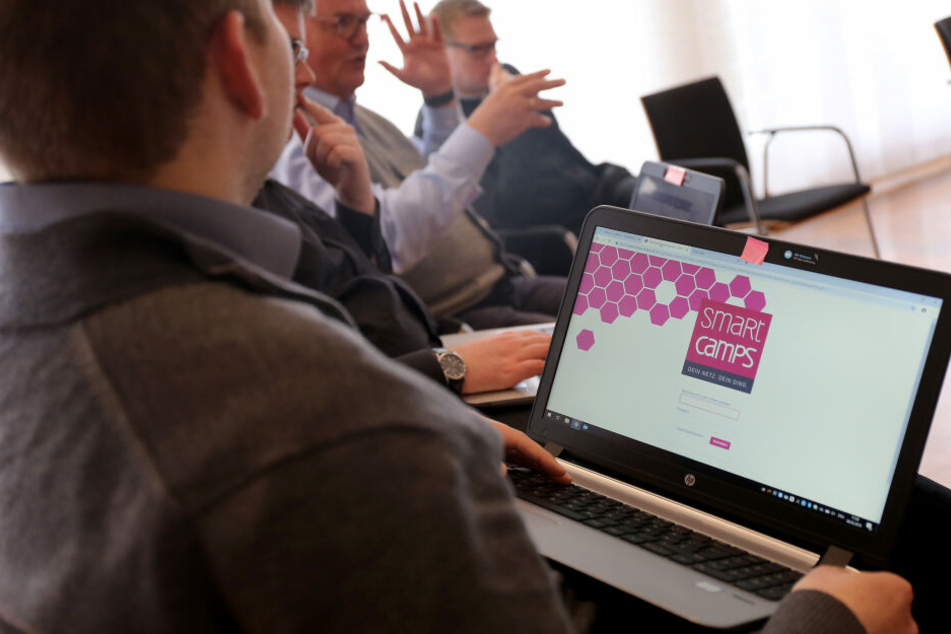 Priesteranwärter sitzen mit Laptop in einem Workshop.