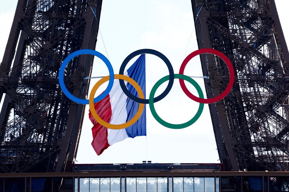 Olympic rings and a French flag are suspended from the Eiffel Tower in Paris.