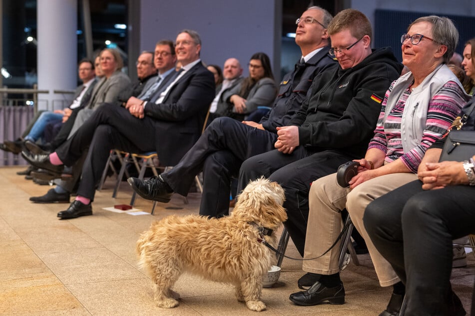 Die damals verschüttete und gerettete Erika Sorm (r.) sitzt mit ihrem Hund Queenie neben Helfern beim Neujahrsempfang der Gemeinde Kröv.