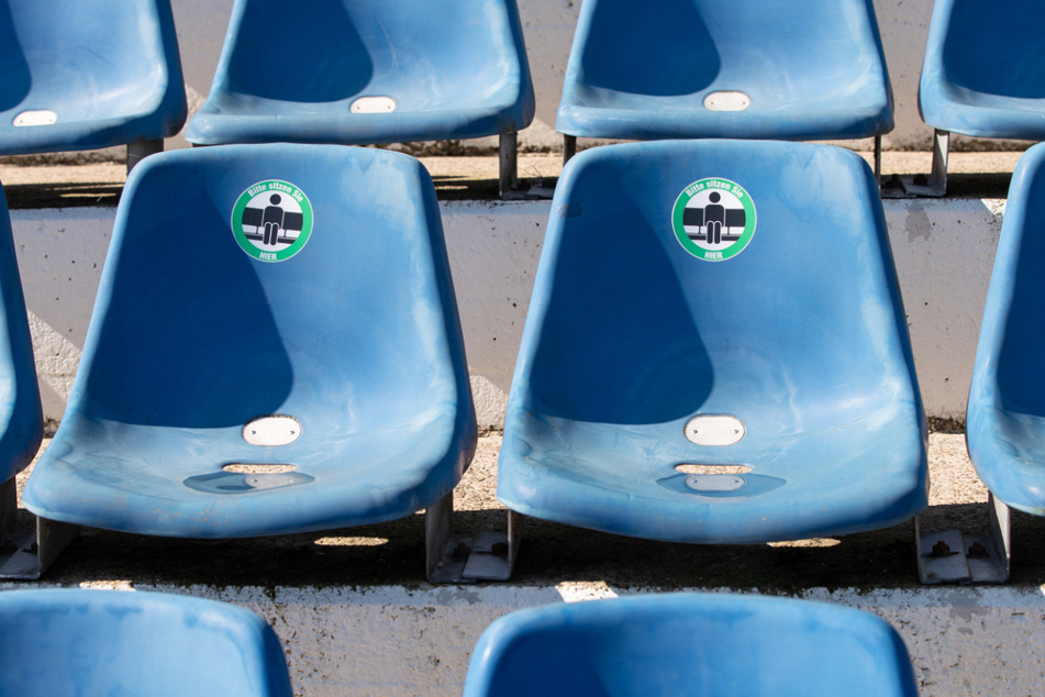 Schilder auf den Sitzplätzen an der Bremer Brücke in Osnabrück zeigen, wo die Fans sich hinsetzen sollen. Zunächst fällt das Eröffnungsspiel aus - es kommen also erstmal keine Anhänger ins Stadion.