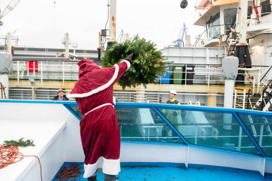 Mit Schwing wirft der Weihnachtsmann die Tanne von einem Schiff zum anderen.