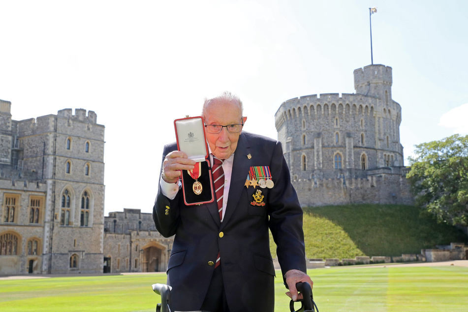 Sir Tom Moore, Weltkriegsveteran und Rekord-Spendensammler, zeigt nach seinem Ritterschlag durch die Queen am Schloss Windsor seine Medaille.