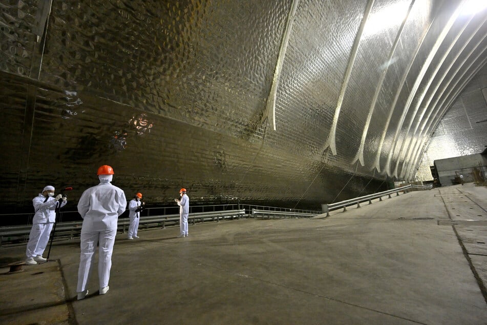 Visitors take pictures in front of the sarcophagus covering the destroyed fourth reactor at the Chornobyl nuclear power plant on April 24, 2026.