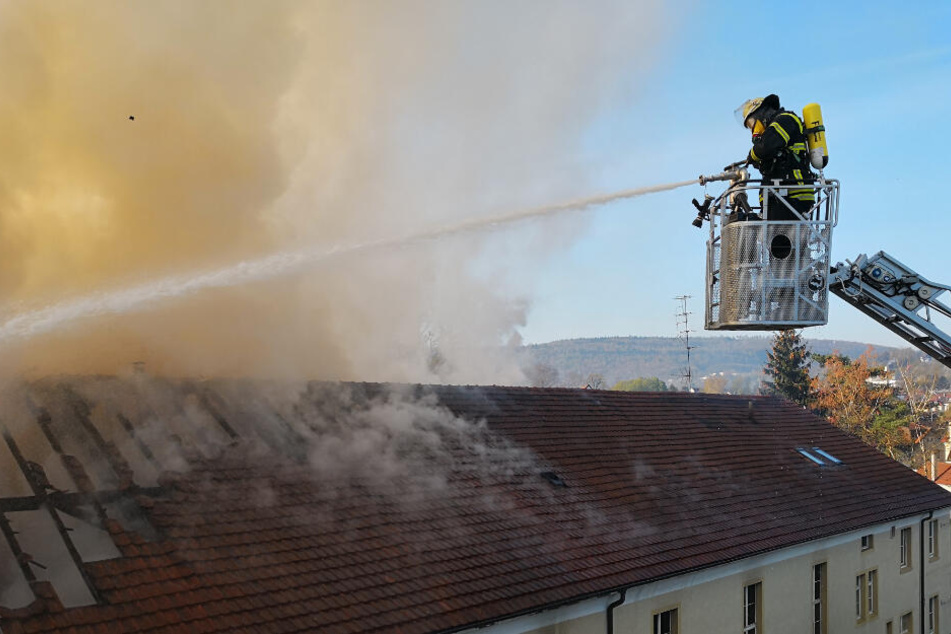 Ein Feuerwehrmann hält einen Wasserschlauch auf das brennende Haus.