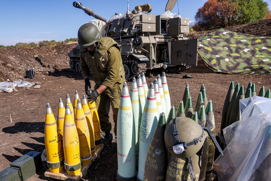 An Israeli army soldier adjusts the tip to a 155mm artillery shell near a self-propelled howitzer deployed at a position near the border with Lebanon on October 18, 2023.