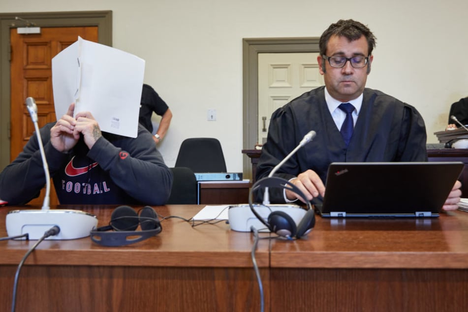 Der Angeklagte (links) und sein Anwalt sitzen in einem Sitzungssaal des Strafjustizgebäudes.