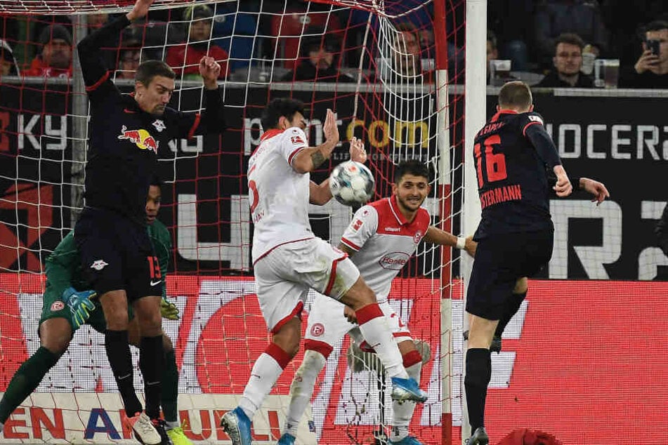 Lukas Klostermann (r.) schießt, Abwehrspieler Kaan Ayhan dreht sich nach links hinten weg, bekommt den Ball an den Unterarm und verursachte so einen Elfmeter.
