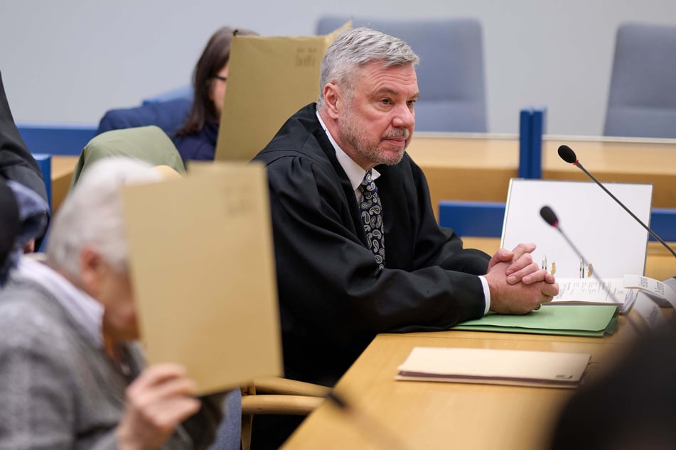 Die angeklagte Großmutter (80, l.) und die angeklagte Mutter (M.) verbergen im Gerichtssaal ihre Gesichter hinter Akten. Zwischen ihnen sitzt Rechtsanwalt Peter Endemann.