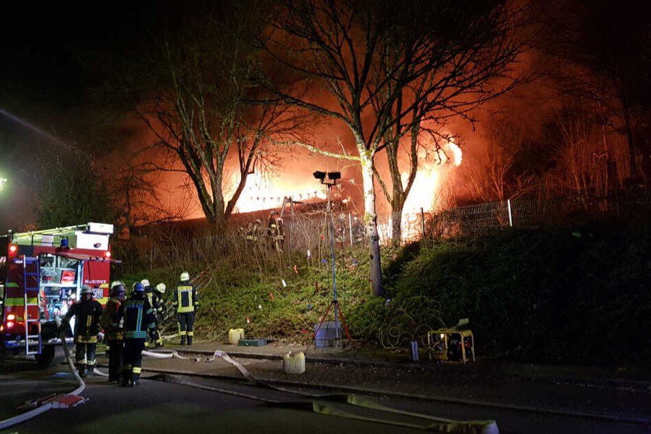 Feuerwehrleute vor dem brennenden Gebäude.