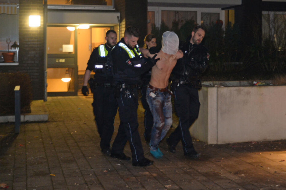 Die Polizei führte den Mann mit einem Spucknetz über dem Kopf ab.