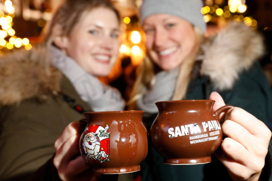 Dazu ist Glühwein da: Zwei Frauen stoßen mit dem Heißgetränk auf einem Hamburger Weihnachtsmarkt an. (Archivbild)