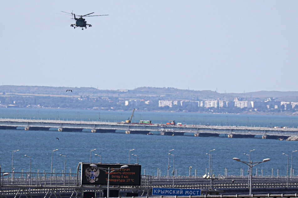 Ein russischer Militärhubschrauber überfliegt über der Straße von Kertsch die Krim-Brücke. Über der annektierten Schwarzmeer-Halbinsel Krim soll es laut russischen Angaben erneut zu Drohnenangriffen gekommen sein.