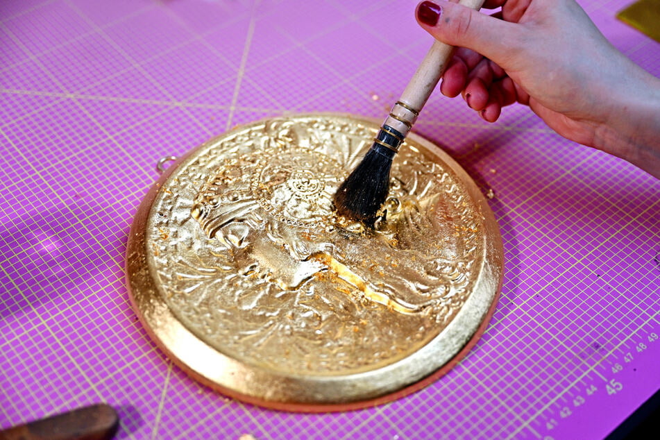 Es gibt mehrere Vergoldungs-Techniken. Hier sieht man die Öl-Vergoldung, bei der das Gold an einer Ölschicht haften bleibt, indem es mit einem Pinsel angedrückt wird.