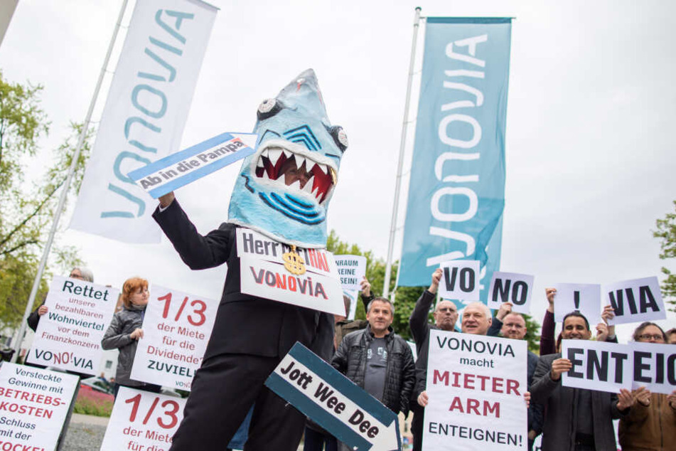 Ein Demonstrant in einem Hai-Kostüm mit einem Schild um den Hals "Herr Miethai Vonovia" steht vor der Vonovia Hauptversammlung vor dem Ruhrcongress.
