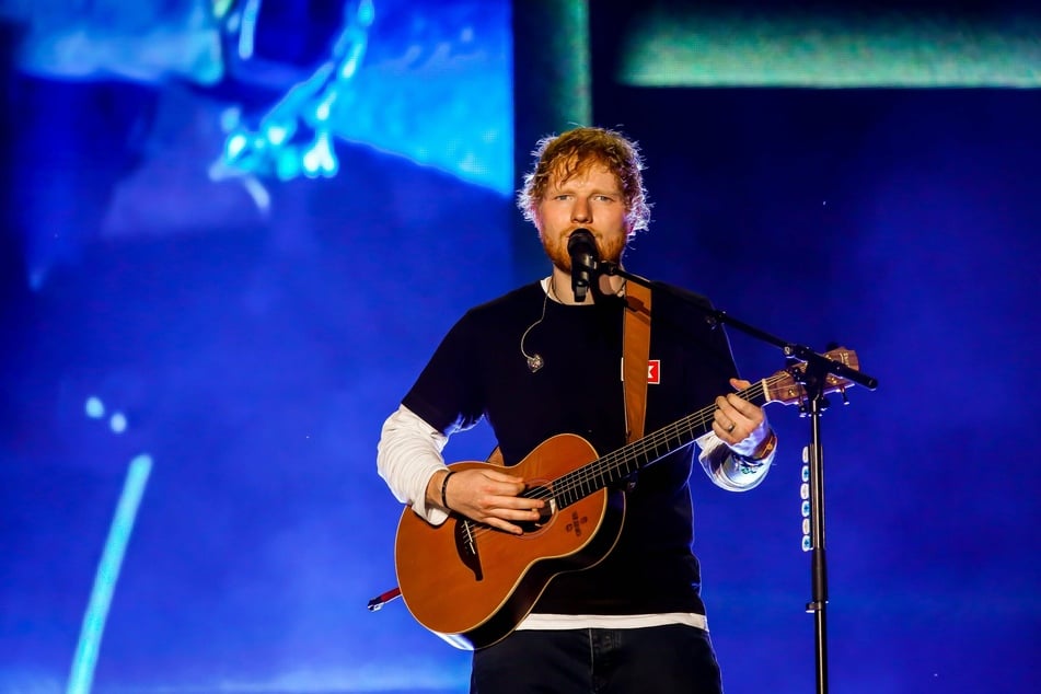 Ed Sheeran performs on a stage.