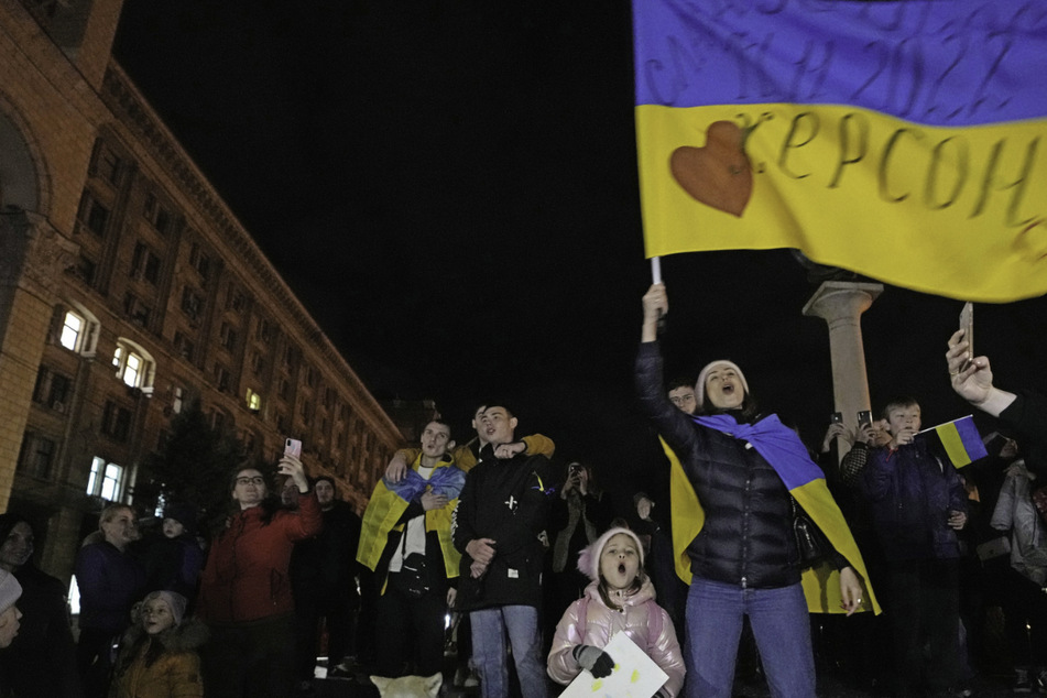 Menschen jubeln und schwenken eine ukrainische Fahne, als sie erfahren, dass ukrainische Truppen in die Region Cherson erfolgreich eingedrungen sind.