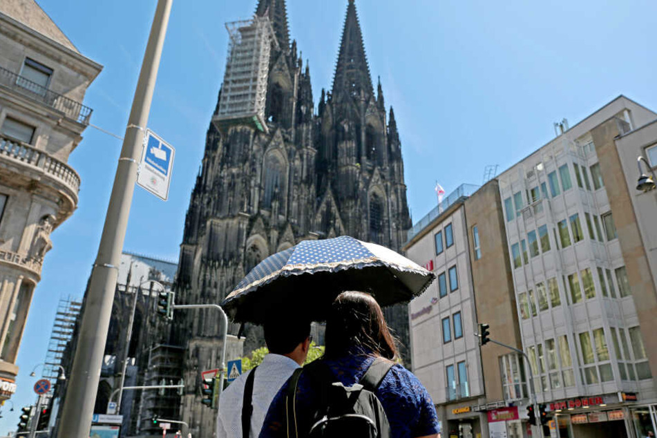 In Köln laufen die Touristen bereits mit Sonnenschirmen durch die Altstadt und schauen sich die Sehenswürdigkeiten wie den Kölner Dom an.