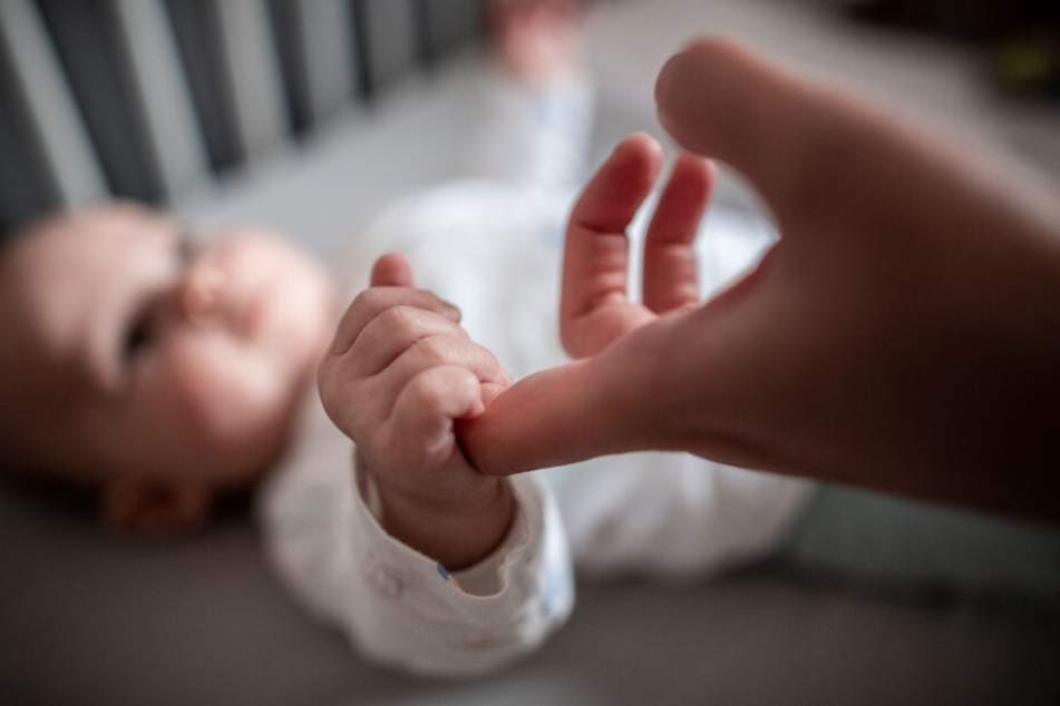 Ein Baby fasst den Finger seiner Mutter an.