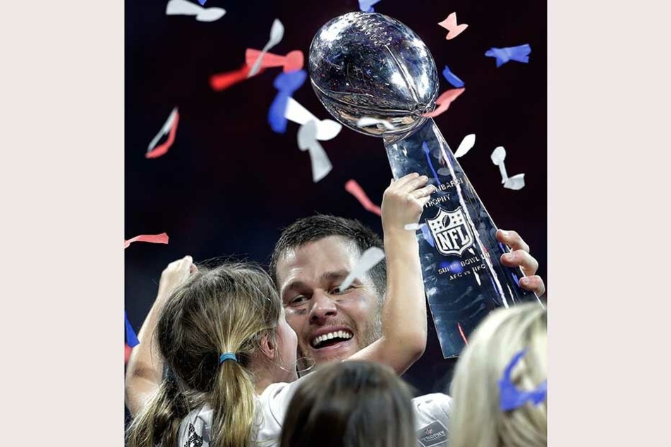 Tom Brady von den Patriots hält nach dem gewonnenen Spiel seine Tocher und die Vince Lombardi Trophäe.