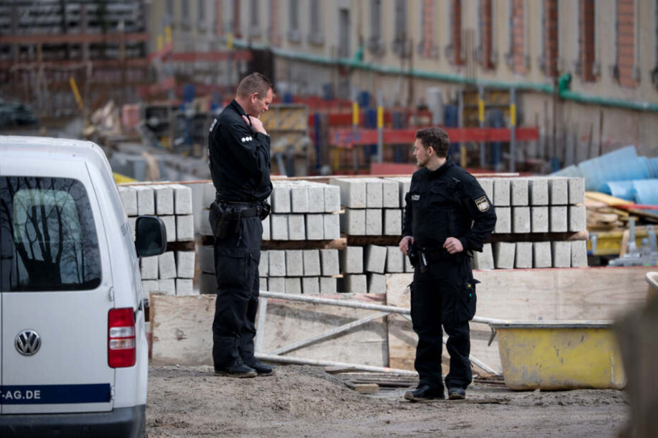 Zwei Polizisten stehen auf einer Baustelle: Hier wurden zwei tote Männer gefunden.