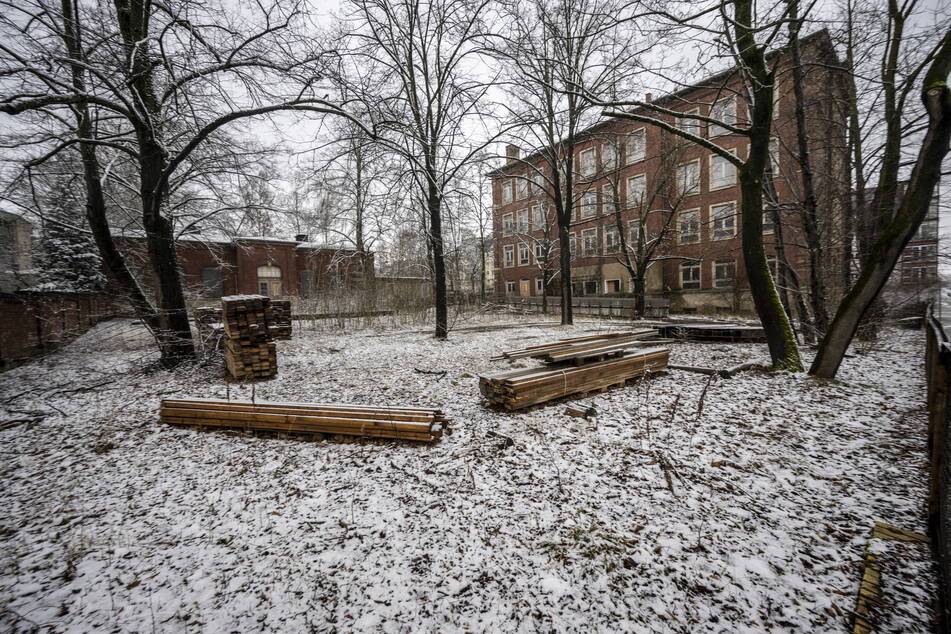 Hinter der Schule in der Charlottenstraße lagert Baumaterial, das Gebäude wirkt verwahrlost.