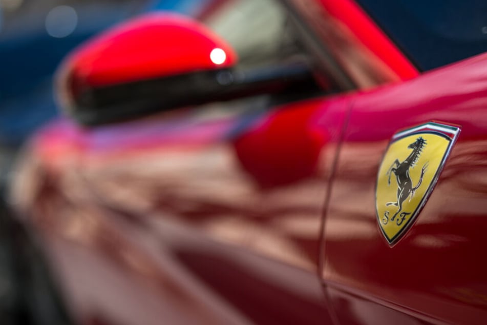 Das Logo des italienischen Sportwagen-Automobilherstellers Ferrari steht an der Seite eines Ferrari F12 Berlinetta. (Symbolbild)