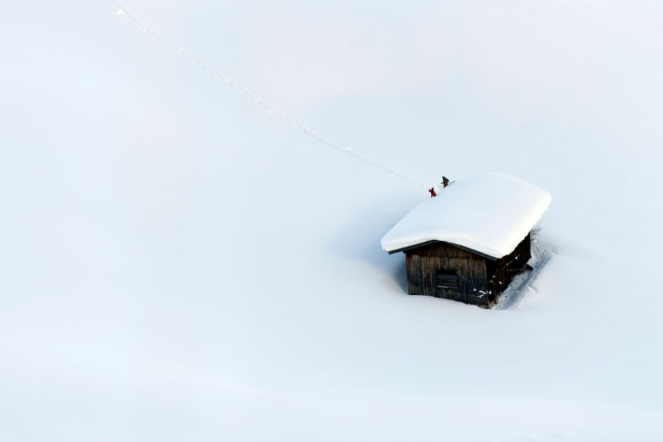 Ein Haus in Österreich in den Schneemassen: Menschen räumen das Dach frei.