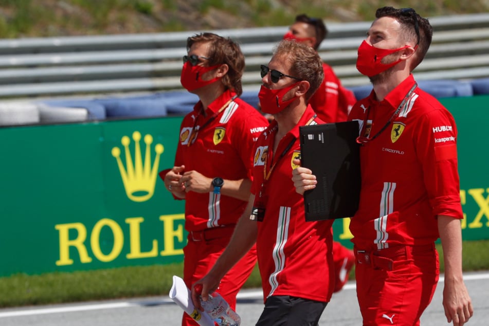 Sebastian Vettel (M) aus Deutschland vom Team Ferrari inspiziert mit seinem Team die Strecke.