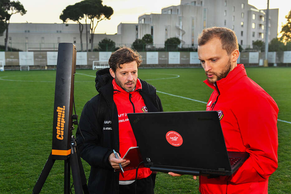 Fitnesscoach Philippe Hasler (l.) und Sportwissenschaftler Jacob Wolf überwachen die eingehenden Daten der einzelnen Dynamo-Spieler, beginnen noch auf dem Platz mit der Auswertung.