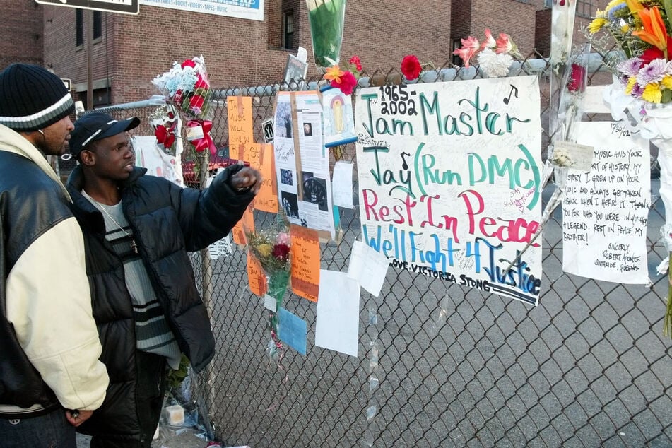 Olel Right (l) and Lionel Frazer (r) look at a wall of flowers and cards outside a music studio in Queens, New York, October 31, 2002, where former Run DMC member Jason Mizell, who was also known as DJ Jam Master Jay, was shot and killed late on October 30.