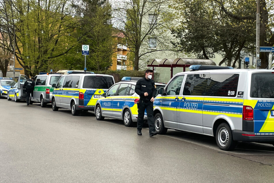 Einsatzfahrzeuge der Polizei stehen vor einem Mehrfamilienhaus, in dem eine 52-jährige Frau tot aufgefunden wurde.