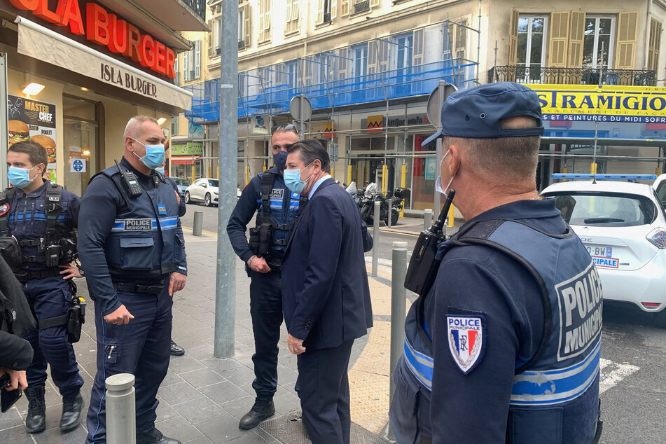 Christian Estrosi (2.v.r), Bürgermeister von Nizza, spricht mit Polizeibeamten am Ort des Messerangriffs.