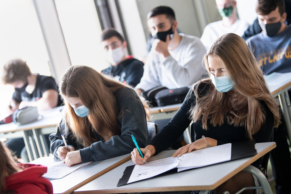 Schülerinnen und Schüler sitzen mit Mund- und Nasenschutz im Unterricht. In Niedersachsen soll sowohl die Masken- als auch die Testpflicht an Schulen stufenweise wegfallen. (Symbolfoto)