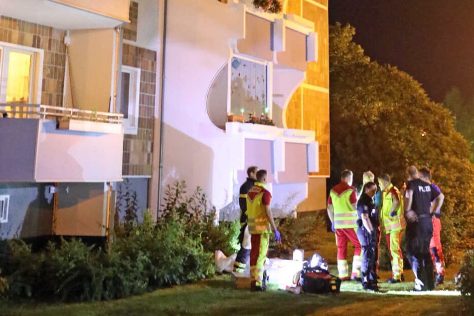 Sanitäter stehen vor dem Wohnhaus, in dem sich die blutige Tat ereignete.