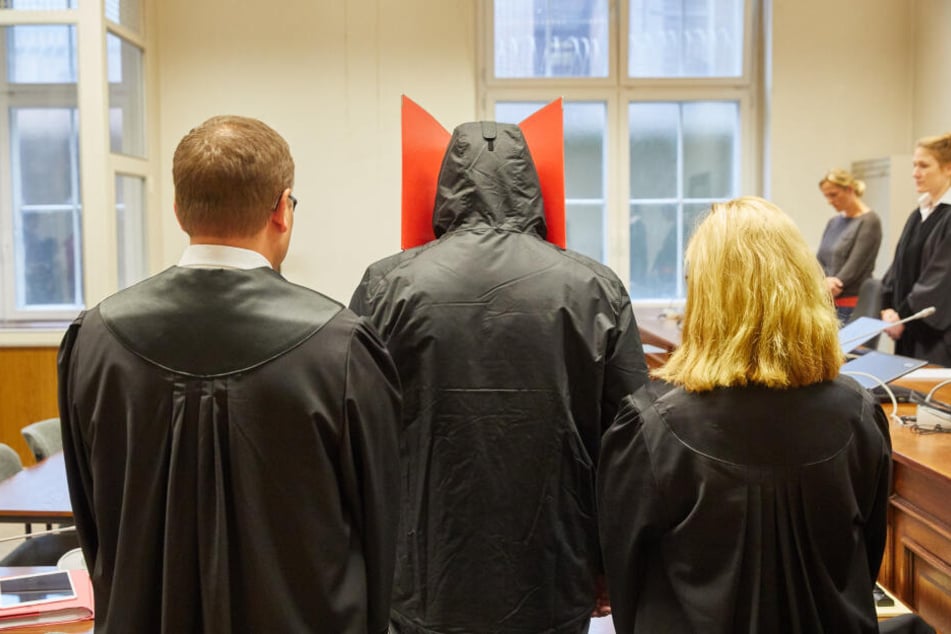 Der Angeklagte (Mitte) steht vor Prozessbeginn wegen Vergewaltigung und gefährlicher Körperverletzung im Strafjustizgebäude.