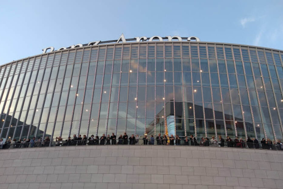 Konzertbesucher der Benz-Arena beobachten das Treiben und Gewusel vor der Halle.