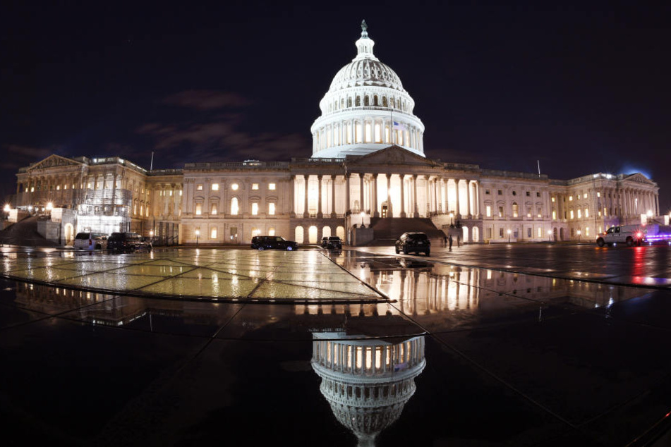 Das Kapitol in Washington spiegelt sich in der Nacht. In den USA sind kurz vor Weihnachten die Regierungsgeschäfte teilweise lahmgelegt.