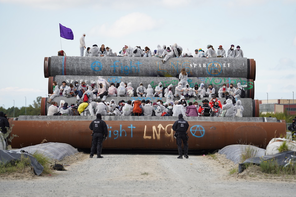 Auf dem Hafengelände von Mukran sitzen Aktivisten auf den Rohren für die geplante Pipeline.