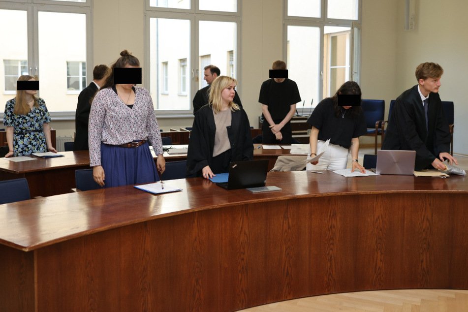 Vier der Angeklagten und die Verteidiger am ersten Prozesstag vor dem Amtsgericht Leipzig.