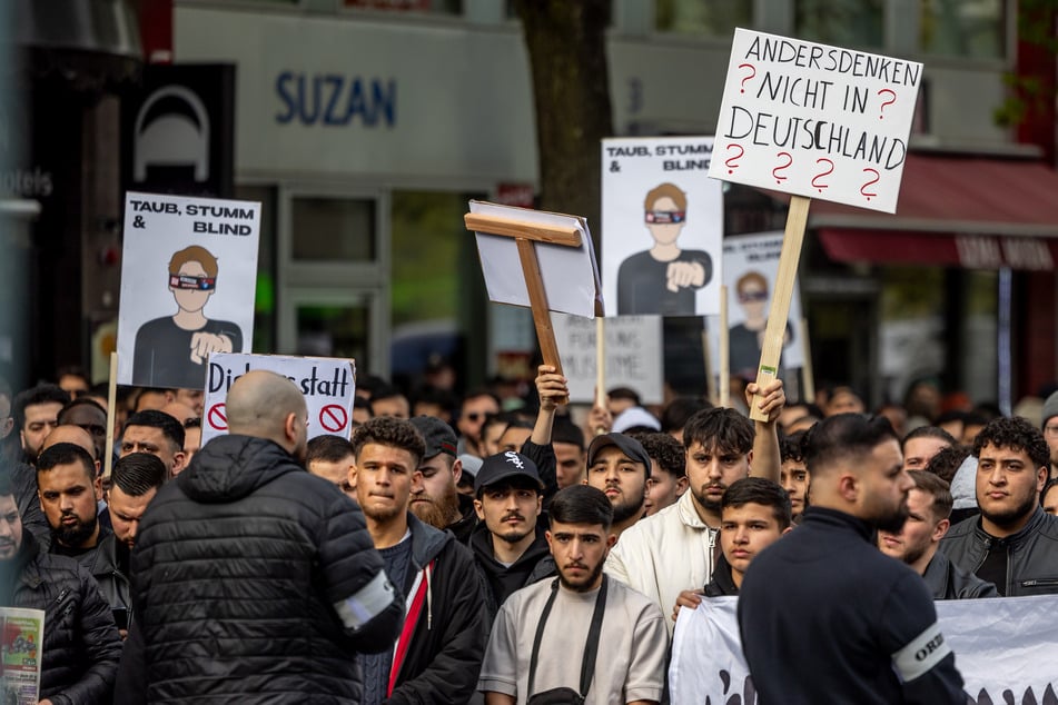 Teilnehmer einer Islamisten-Demo halten ein Plakat mit der Aufschrift "Andersdenken? Nicht in Deutschland" in die Höhe.