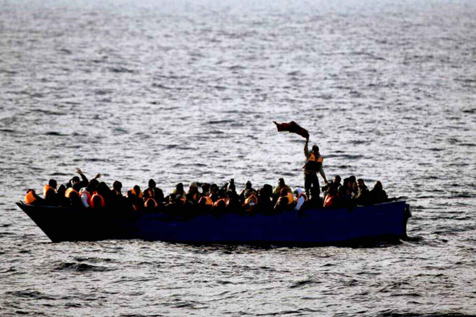 Flüchtlinge aus Afrika rufen auf dem Mittelmeer in einem Boot um Hilfe (Archivbild).