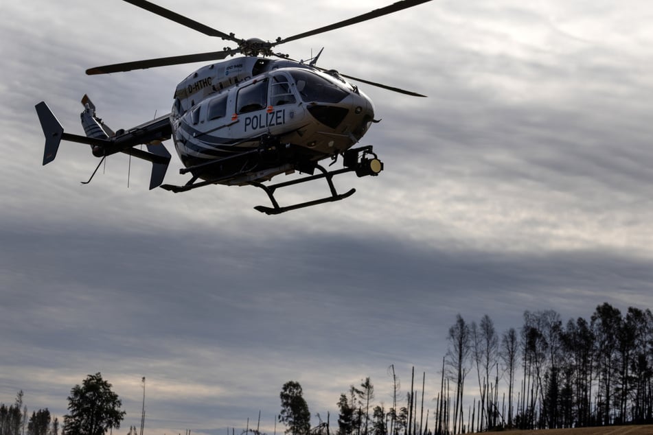Ein Hubschrauber mit Wärmebildkamera sucht am Sonntag nach versteckten Glutnestern beim Waldbrand auf der Saalfelder Höhe.
