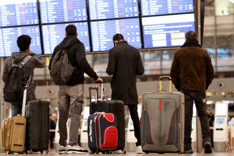 Reisende gucken am Flughafen Hamburg, ob ihr Flug pünktlich ist. (Symbolbild)