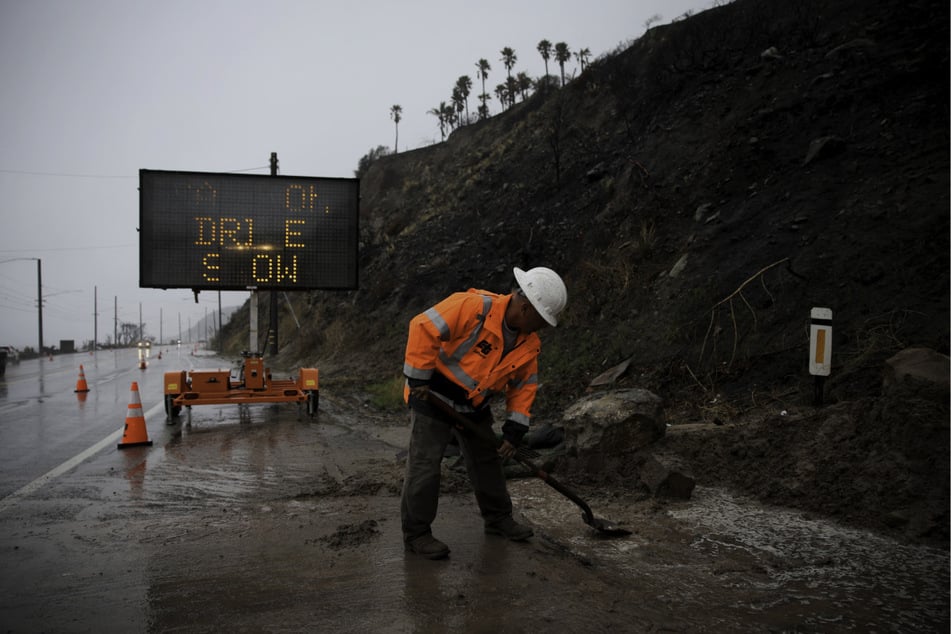 A worker clears debris from a mudslide in the Pacific Coast Highway in the Pacific Palisades burn zone in Los Angeles, California.