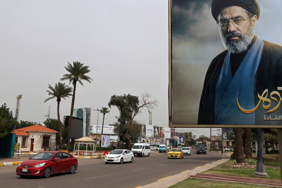 Cars drive past a billboard bearing an image of Iranian Supreme Leader Ayatollah Mojtaba Khamenei near the Iraqi Intelligence Directorate in the Mansour district of Baghdad on March 21, 2026.