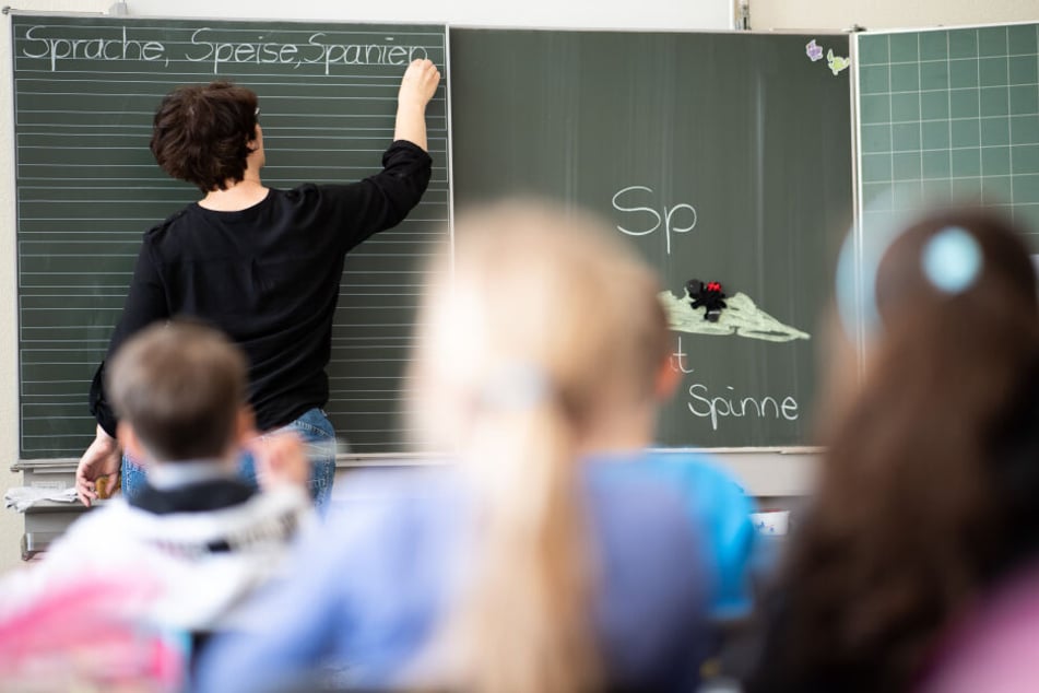 Eine Lehrerin schreibt in einer Grundschule Wörter mit "Sp" am Anfang an eine Tafel.