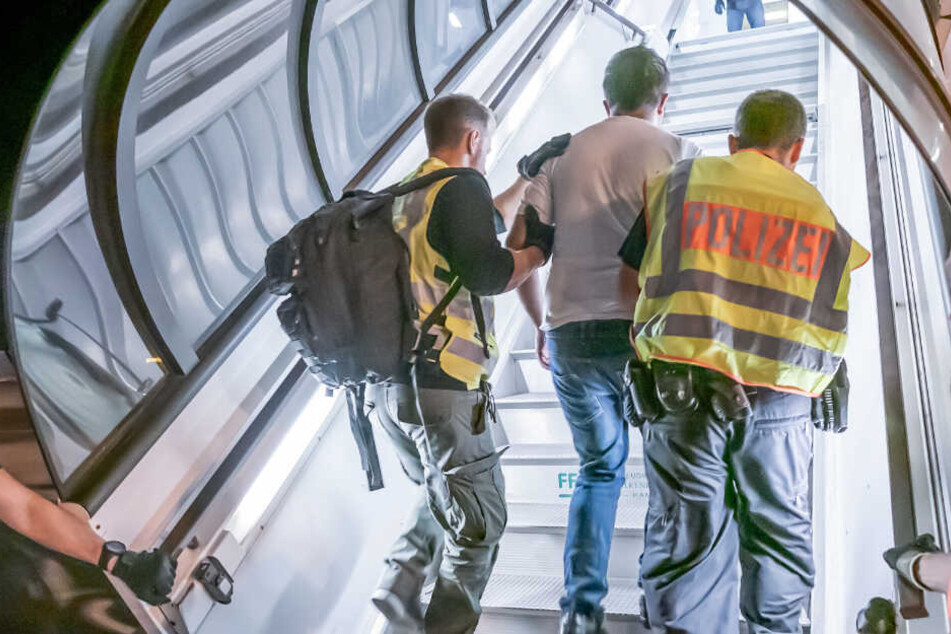 Polizisten begleiten einen Mann in ein Flugzeug. (Symbolbild)