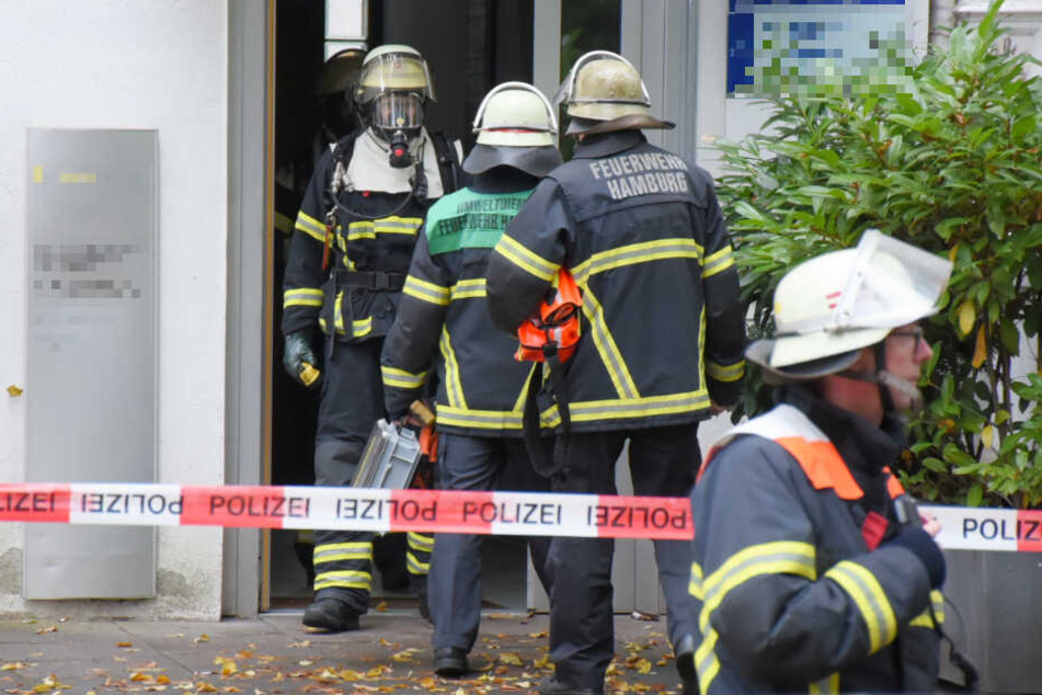 Feuerwehrleute kommen mit Atemmasken aus der Arztpraxis.