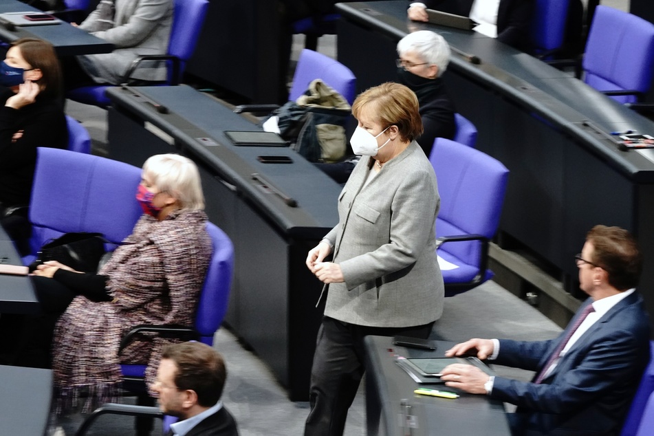 Bundeskanzlerin Angela Merkel (CDU) geht mit Mund-Nasenbedeckung während der Debatte vor der Verabschiedung der Änderung des Infektionsschutzgesetzes , dem Gesetzes zum Schutz der Bevölkerung bei einer epidemischen Lage von nationaler Tragweite, durch den Plenarsaal.