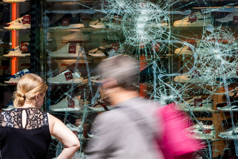 Fußgänger gehen an einem schwer beschädigten Schaufenster eines Geschäfts in der Königstrasse vorbei.